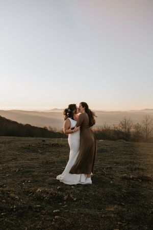 a couple shares a kiss in the sunrise over the mountains of Western North Carolina