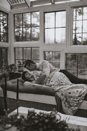A black and white photograph of a couple lay in a greenhouse in Western North Carolina just outside of Asheville