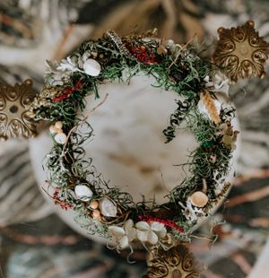 a mossy earthy crown adorned with mushrooms and crystals sits atop of a marble table