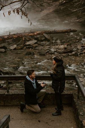 a man proposes to his girlfriend on an icy morning by a waterfall in the mountains of Western North Carolina near Asheville