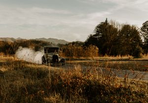 a vintage truck does a burn out and creates a cloud of smoke amidst the field with the Blueridge Mountains in the background