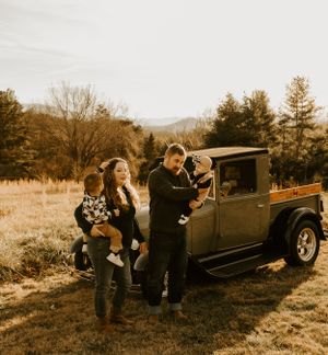 a family with two young children park a vintage truck in the field overlooking the Blueridge mountains in North Carolina