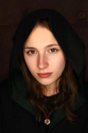 Moody portrait with dark green hood and dramatic lighting.