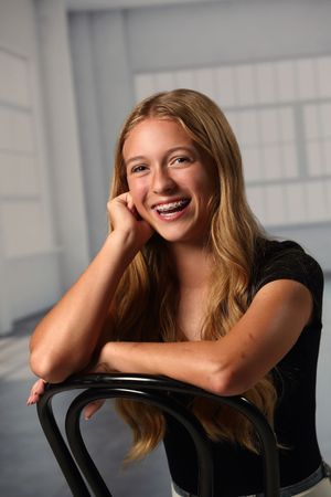 Four artistic portrait shots show a person in a black top leaning against a chair with varying candid poses.