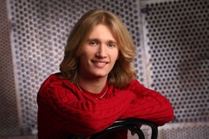 Bright red scarf adds pop of color against metallic perforated background in portrait series.