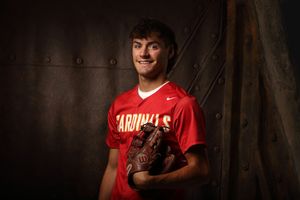 Young baseball player in red Cardinals jersey holding a Wilson glove, posing for a portrait photo.