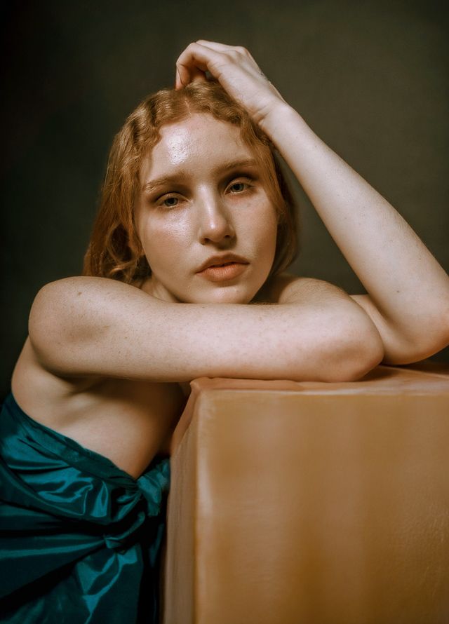 Artistic portrait series showing a figure in teal fabric against a dark background with dramatic lighting.