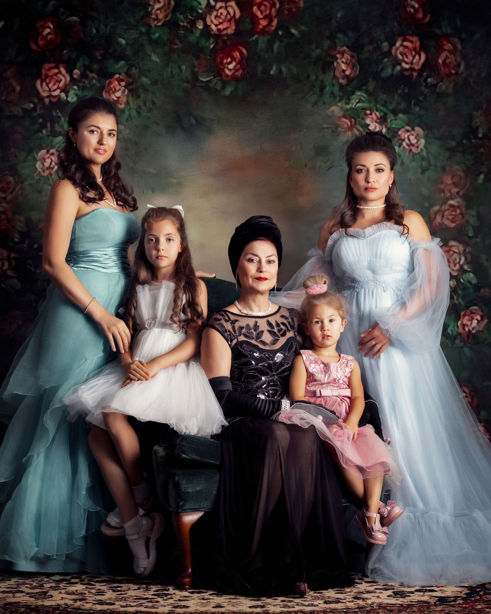 Formal portrait of five people in elegant blue and white gowns against a floral backdrop.
