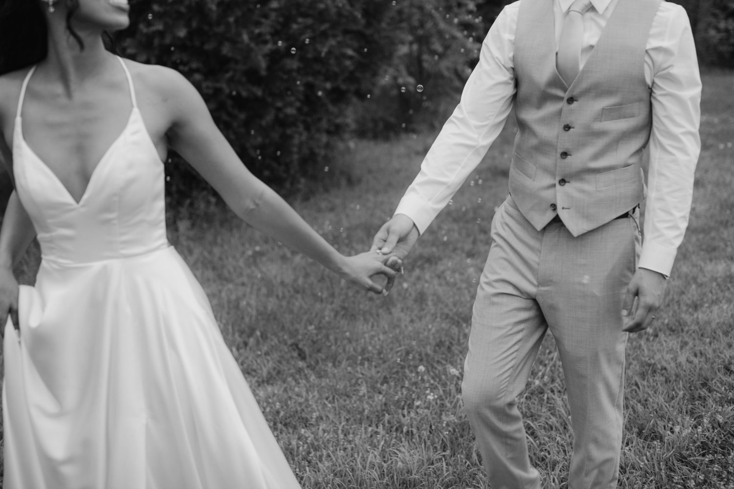A black and white capture of two people holding hands in formal attire.