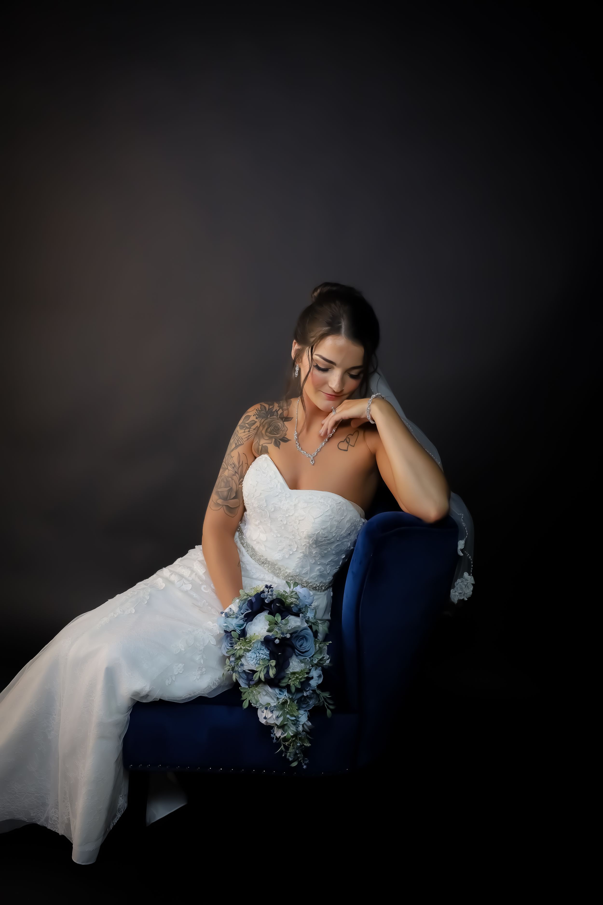 Artistic bridal portrait on blue chaise lounge with cascading white dress.