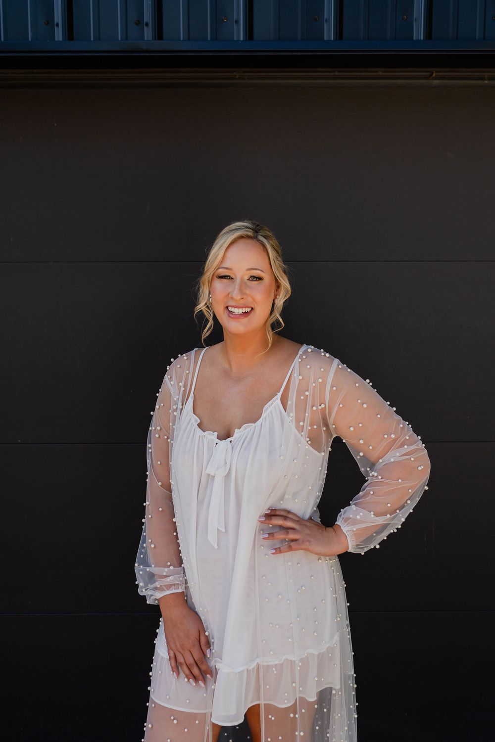 Elegant sheer pearl-beaded overlay jacket in white worn over a sleeveless dress against dark background.