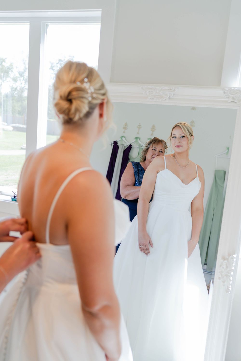 Wedding preparations in a bright white dressing room with reflections in multiple mirrors.