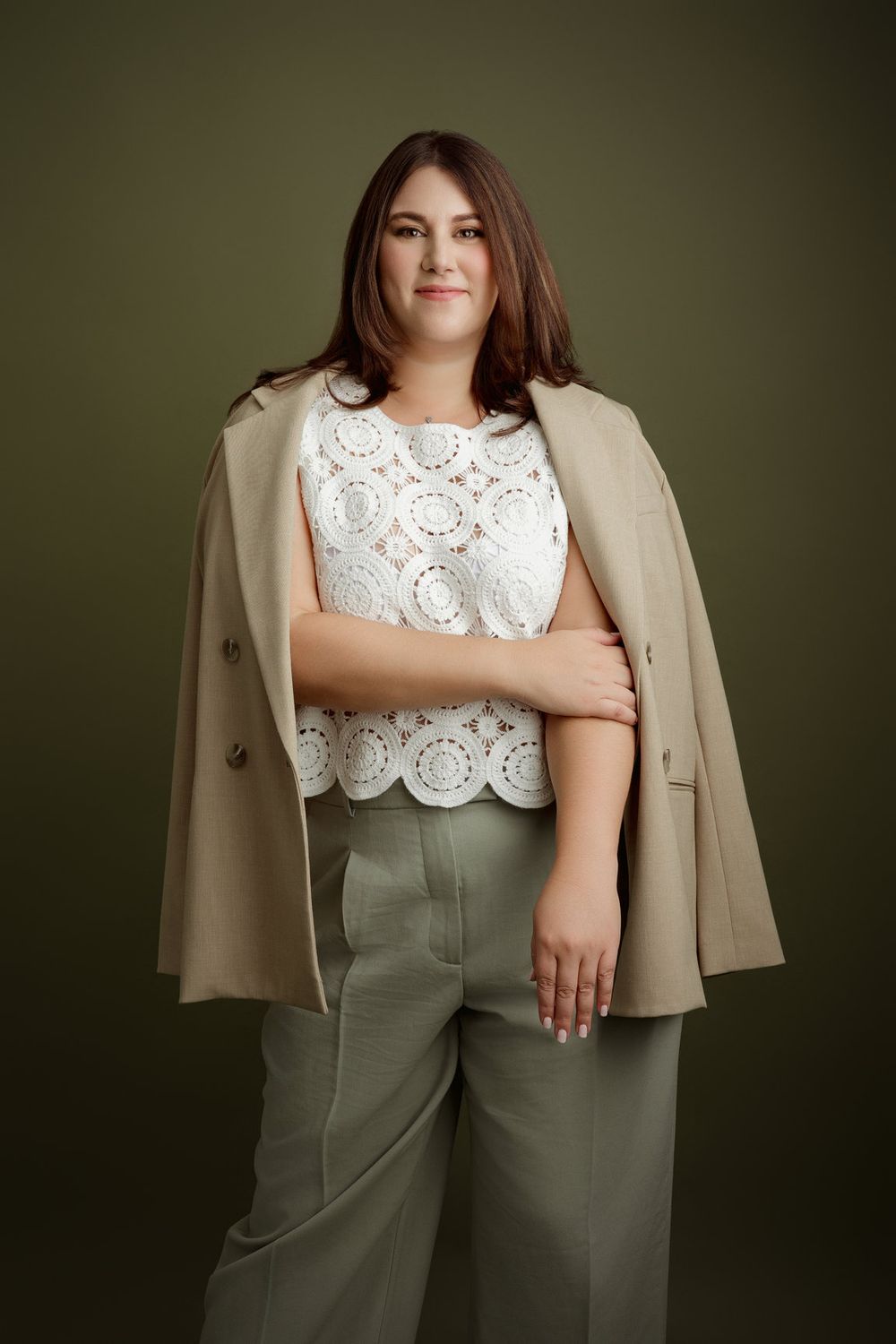 Professional Miami headshot of a woman in a beige suit against a deep green studio background.