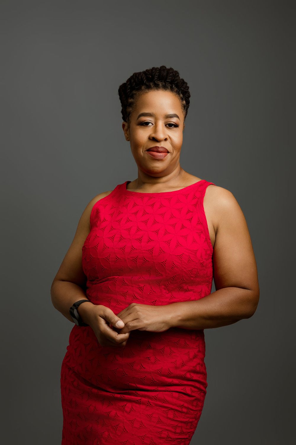 Professional Miami headshot of a woman in a red dress against a dark gray studio background.