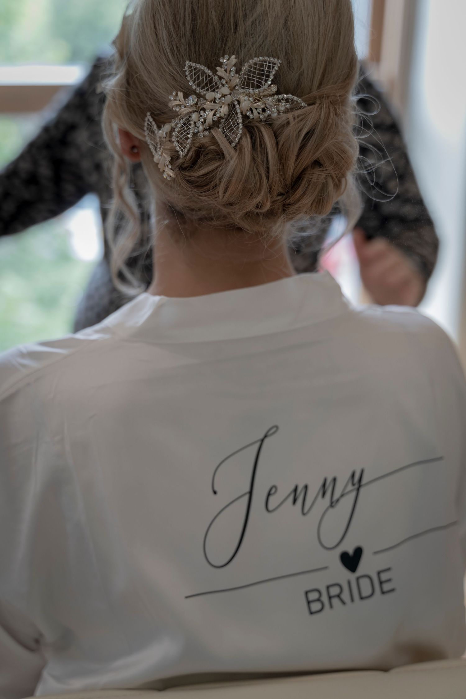 White bridal robe with cursive name and sparkly hair accessory detail.