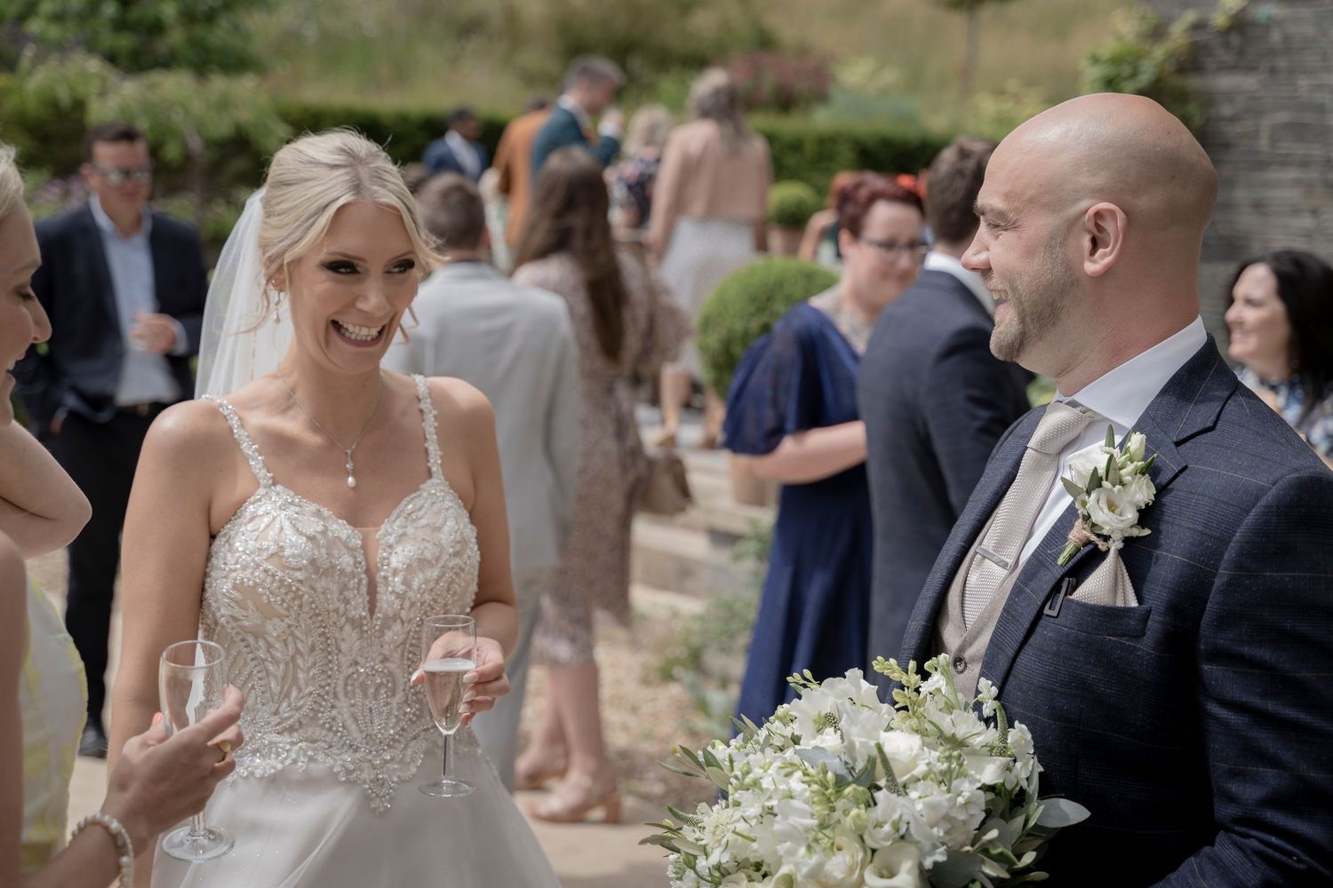 Outdoor wedding reception with guests mingling in garden setting. Bride and Groom. Devon Wedding Photography.