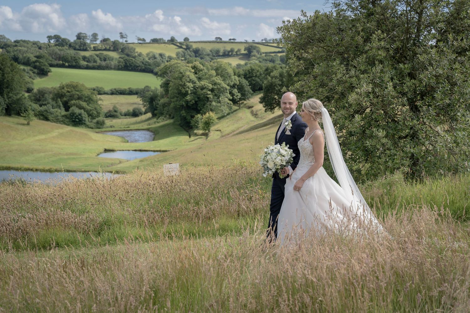 Newlywedsin scenic countryside with rolling hills and lake in background. Shilstone House, Devon Wedding. Devon Photography. Bride.