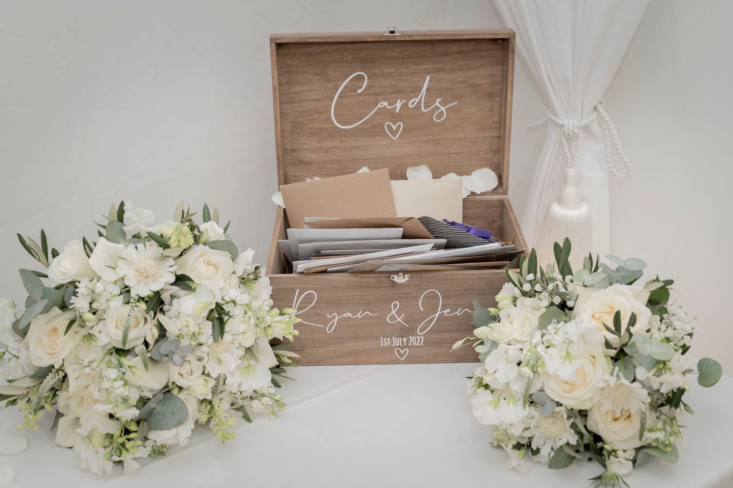 Rustic wooden card box with white floral arrangements on either side.