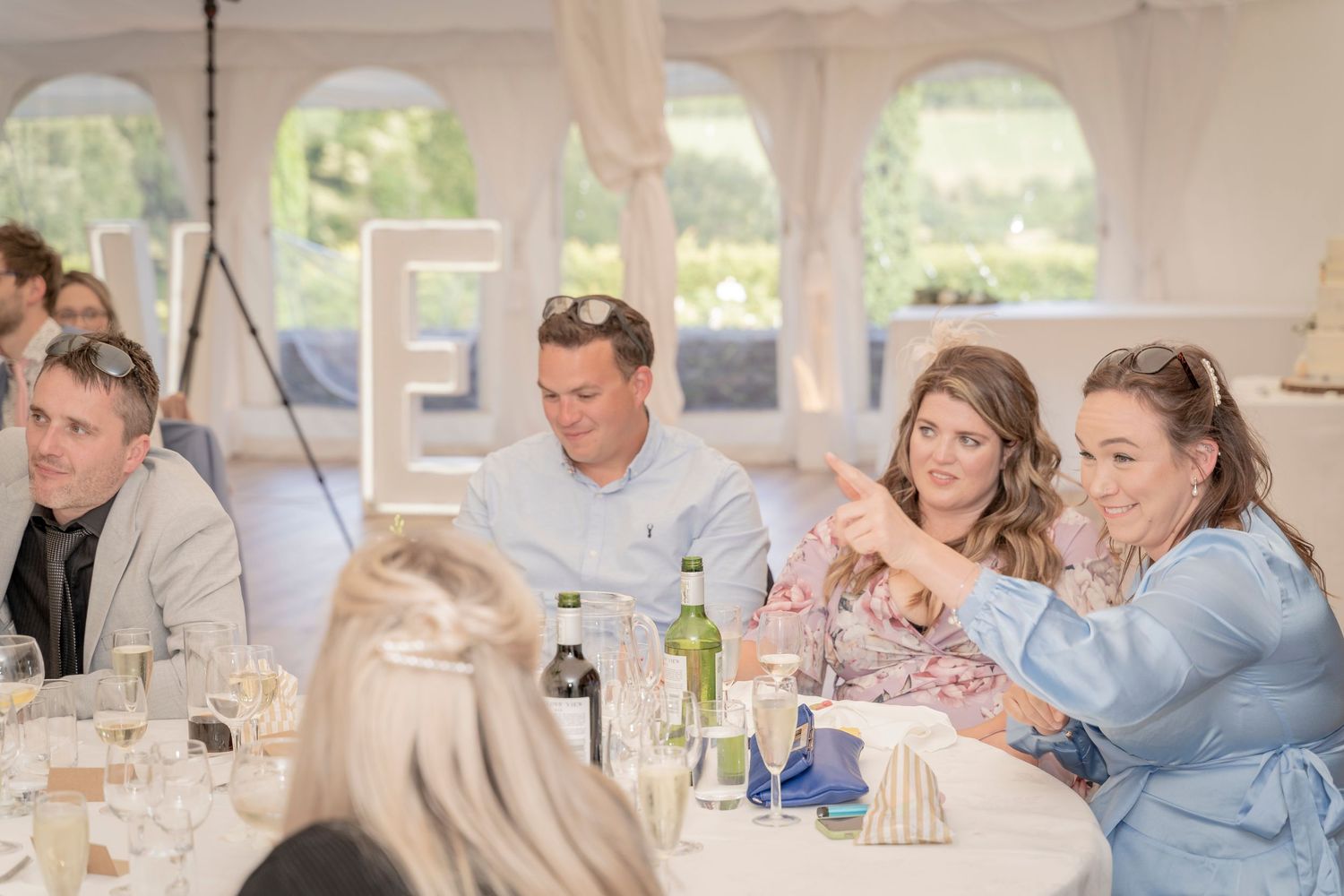 Wedding guests enjoying meal and conversation at reception tables.