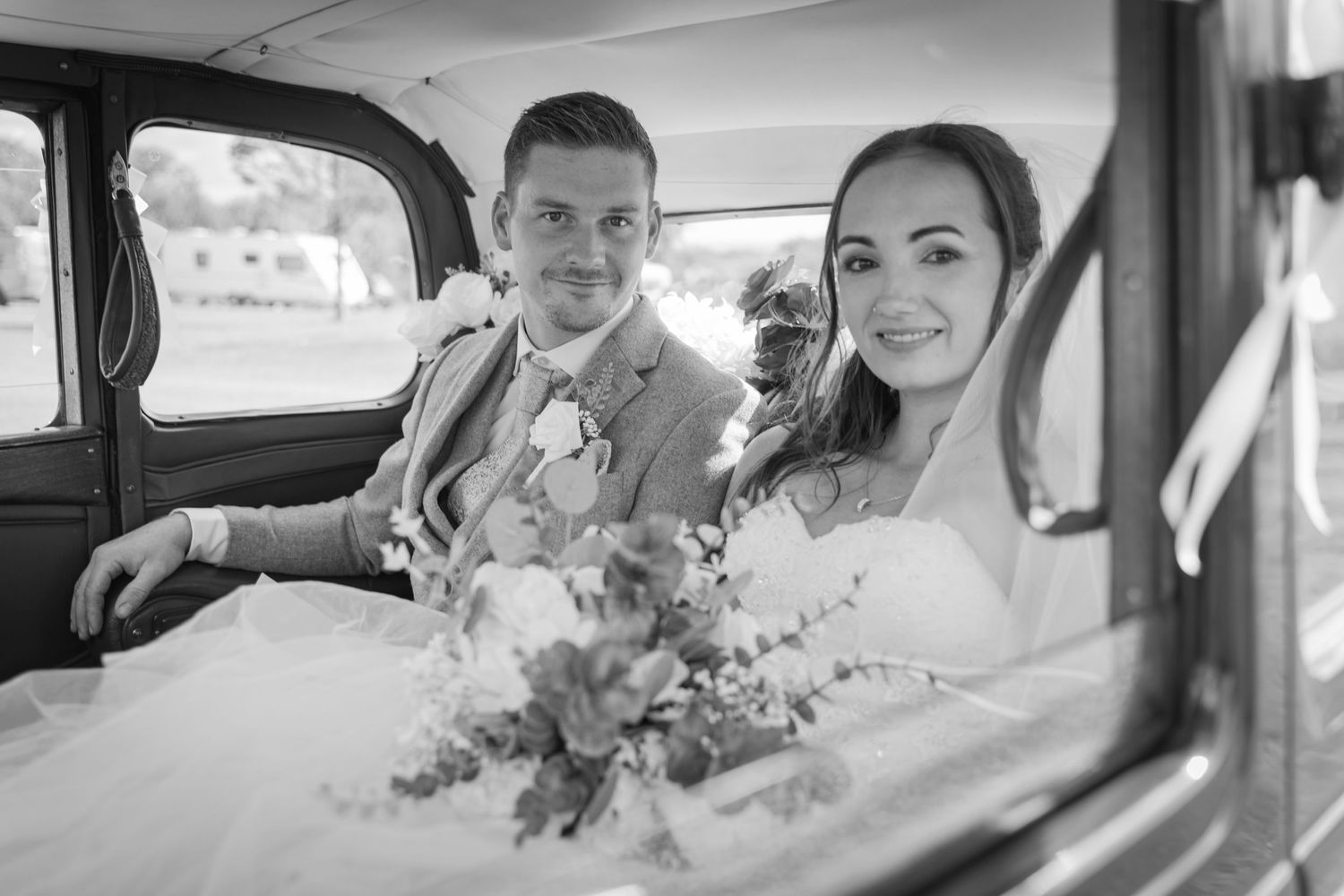 Wedding couple shares joyful moments inside a vintage car.