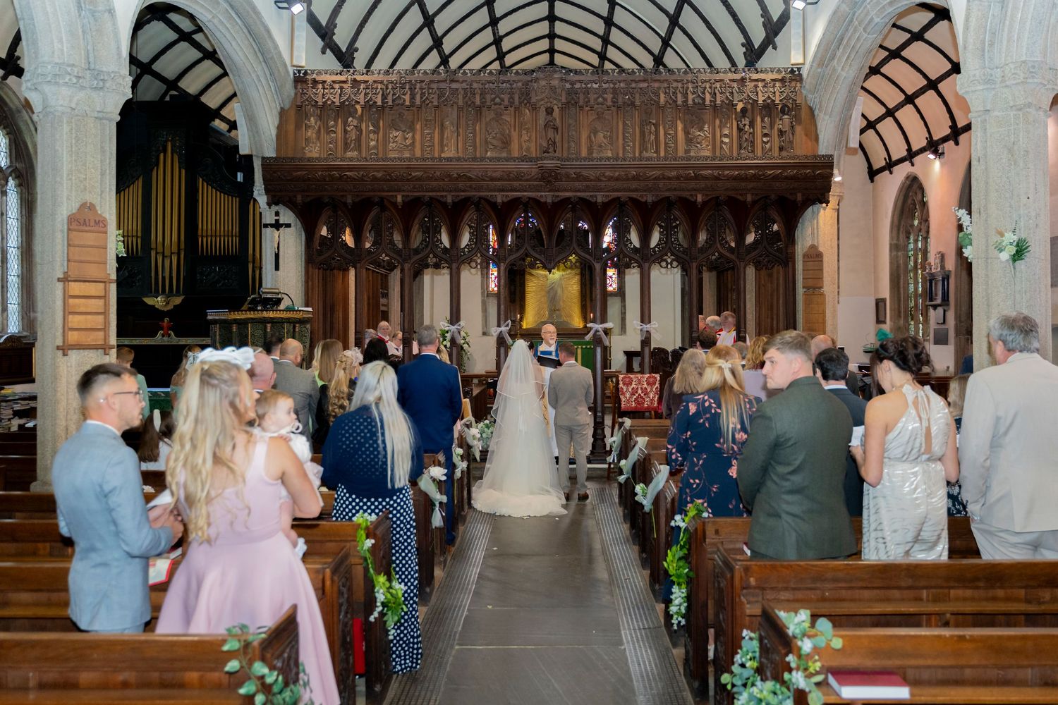 Gothic church interior with vaulted ceiling and ornate woodwork decorated for wedding ceremony.