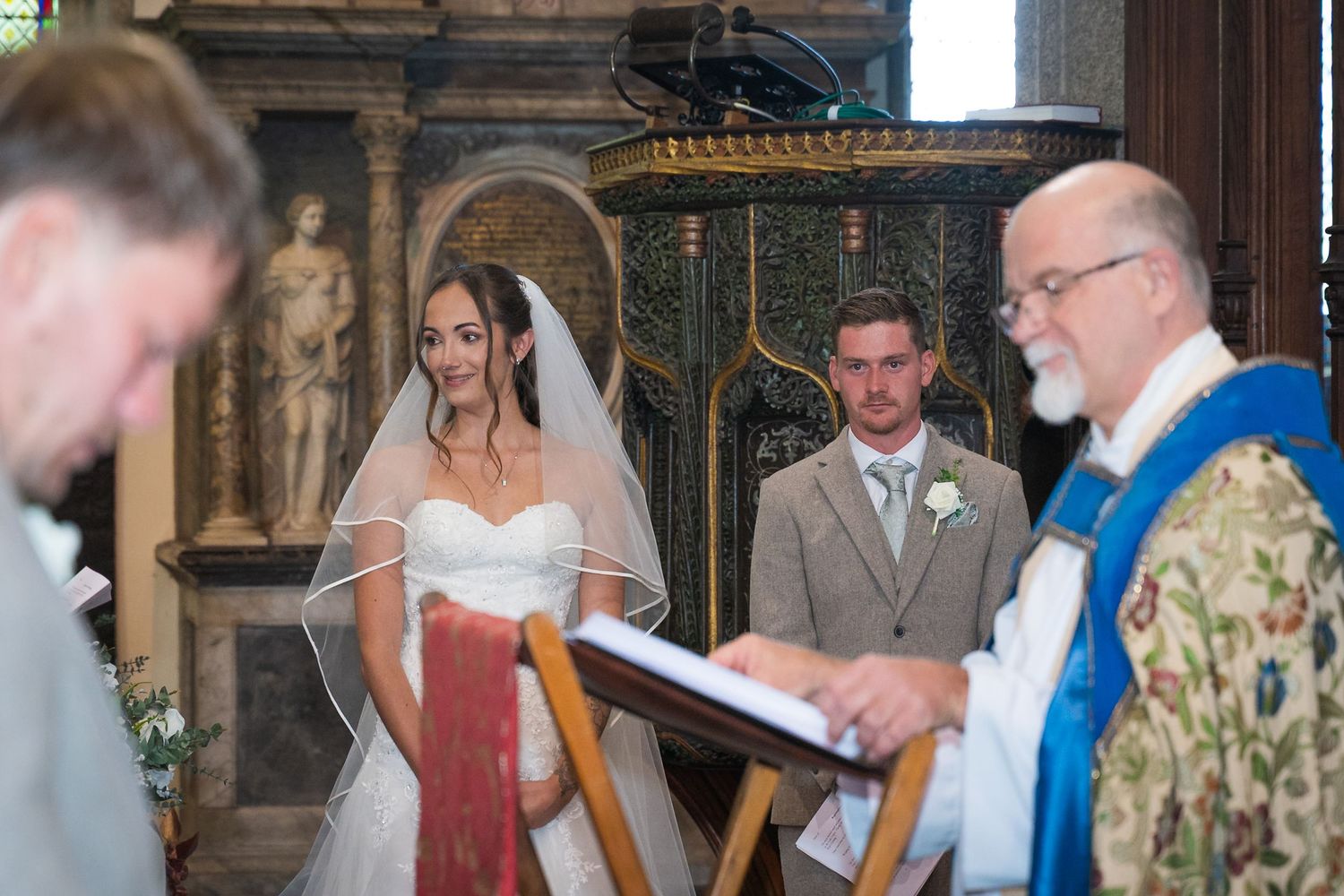Wedding ceremony participants gather in a church for signing documents at the altar.
