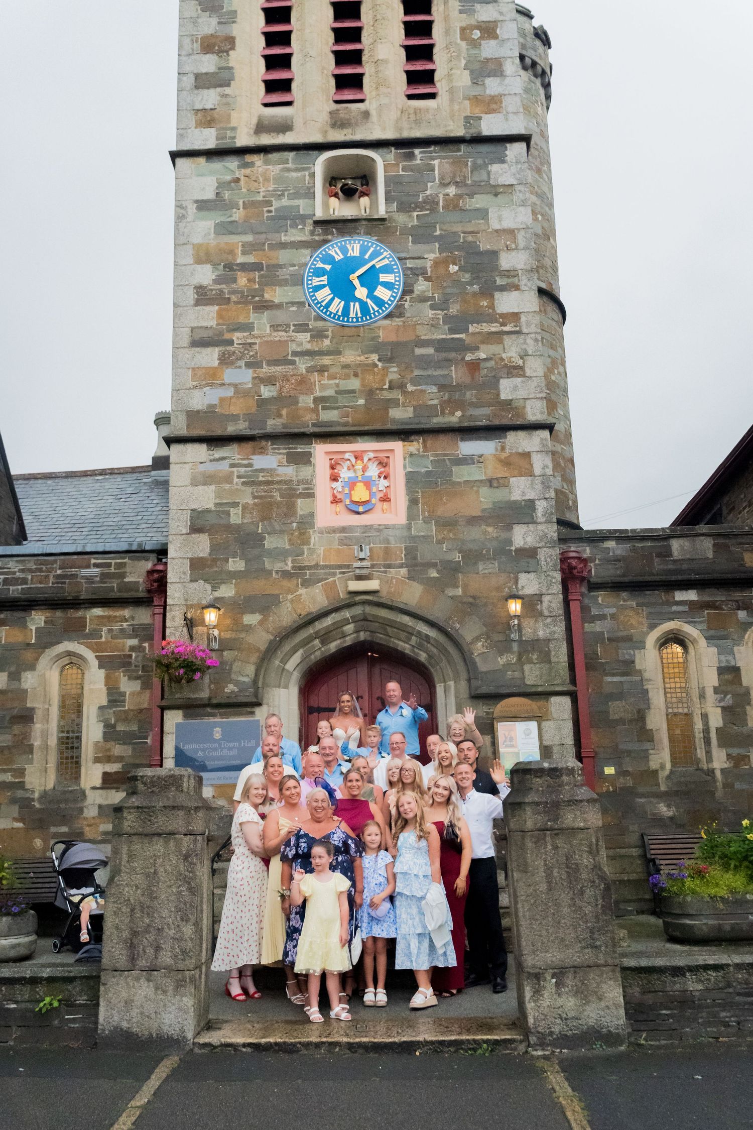 A stone church building with a clock tower and several people gathered at its entrance.