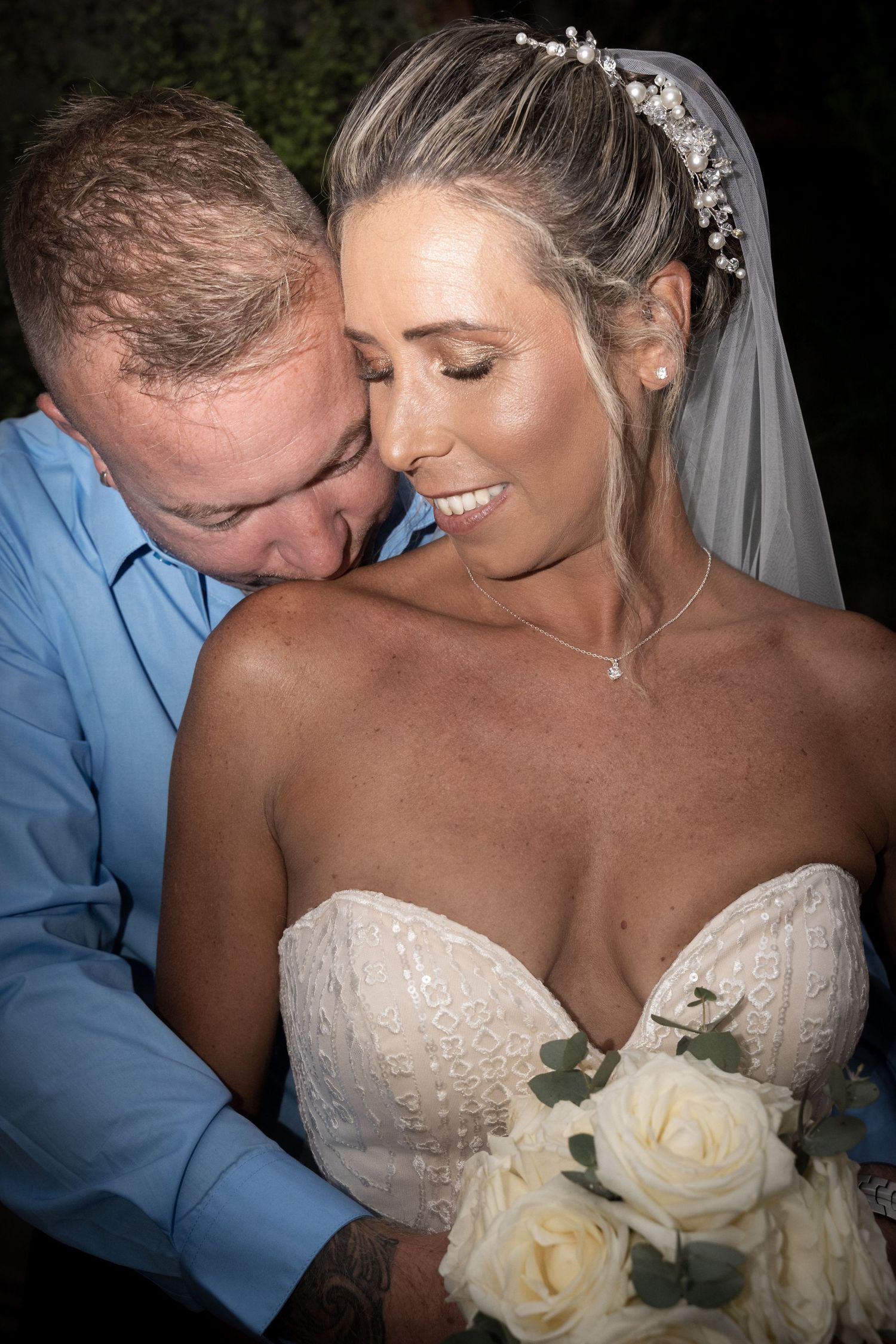 A close-up romantic moment captured with white roses in the foreground.