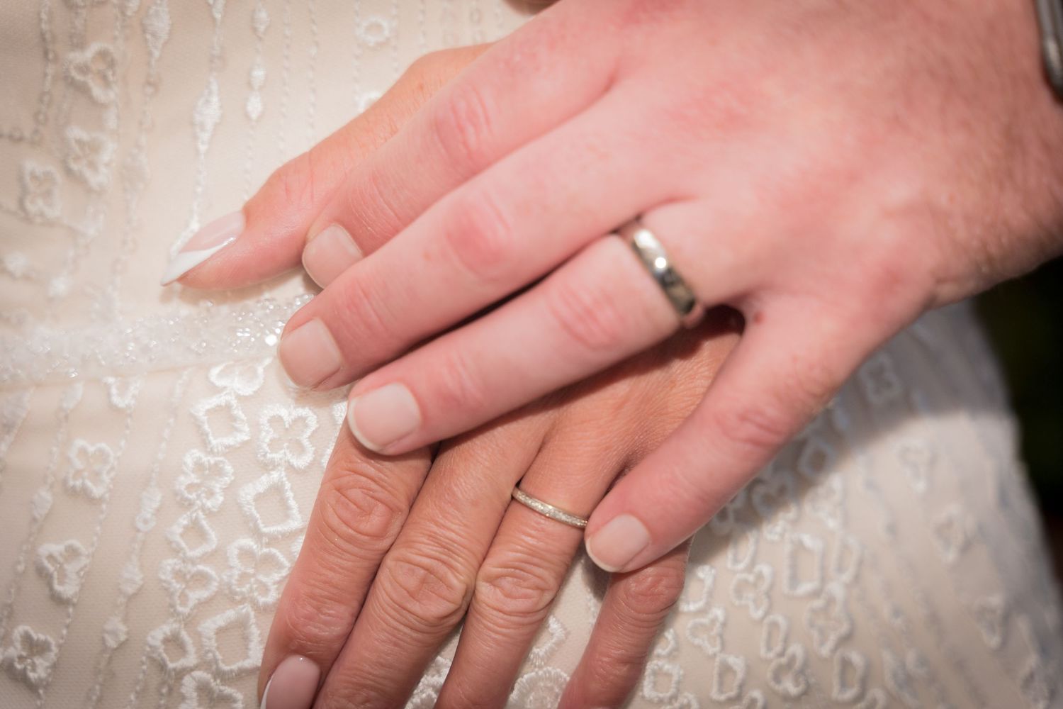 Close-up view of hands exchanging wedding rings during a marriage ceremony.