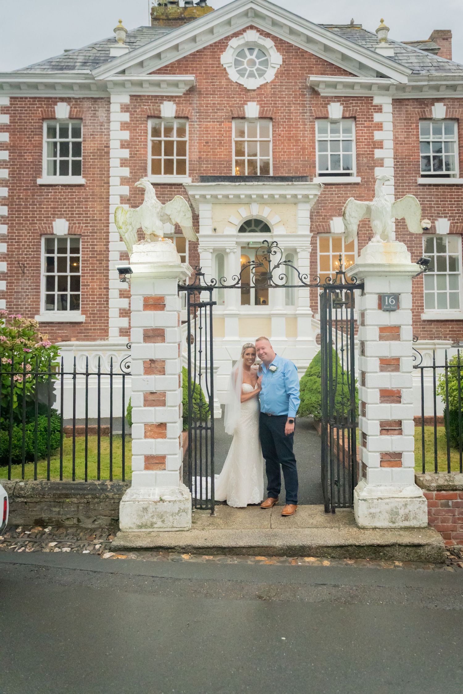 A historic red brick mansion with ornate gates and white stone trim serves as backdrop for a special occasion.