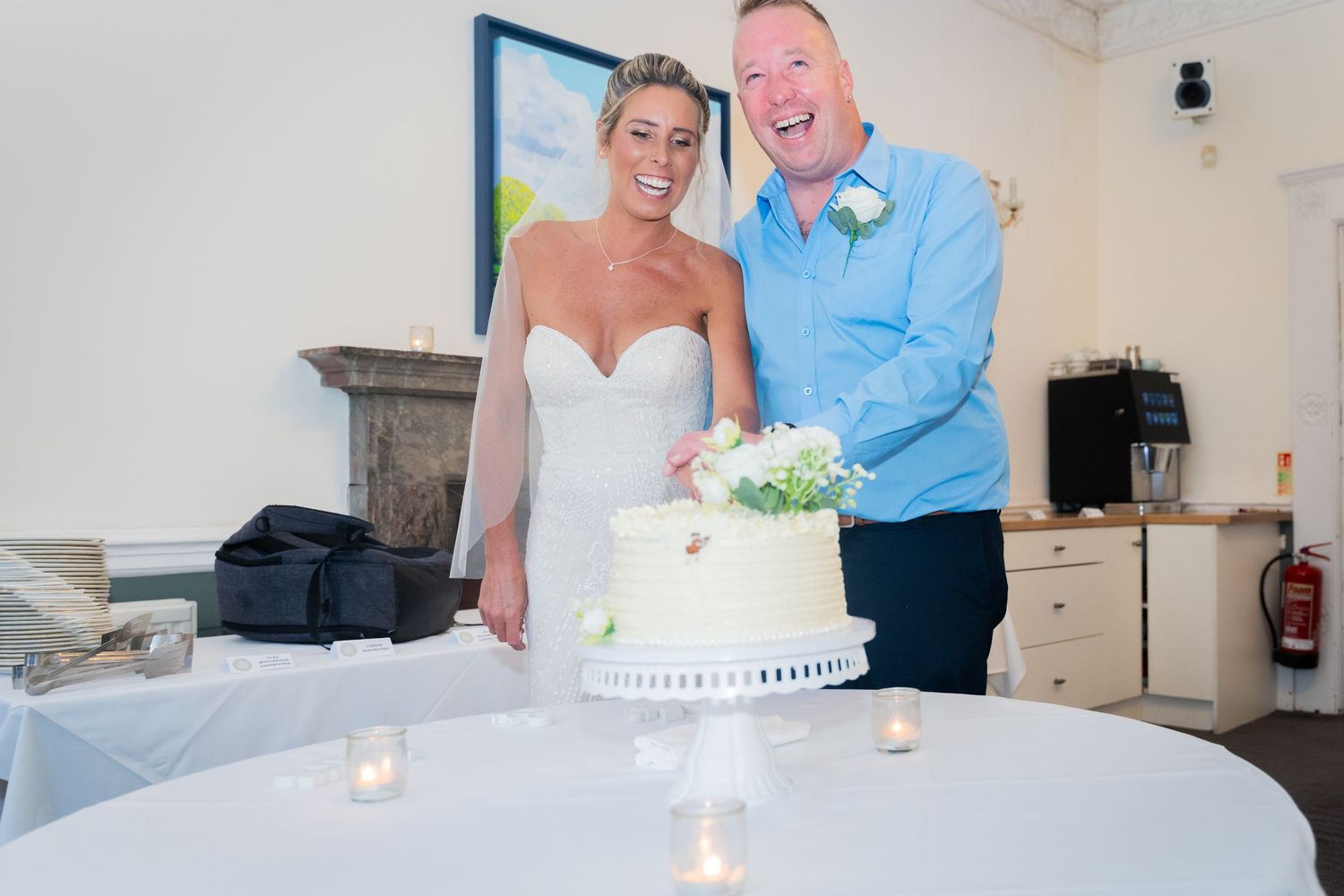 A couple cuts their white wedding cake together during their reception celebration.