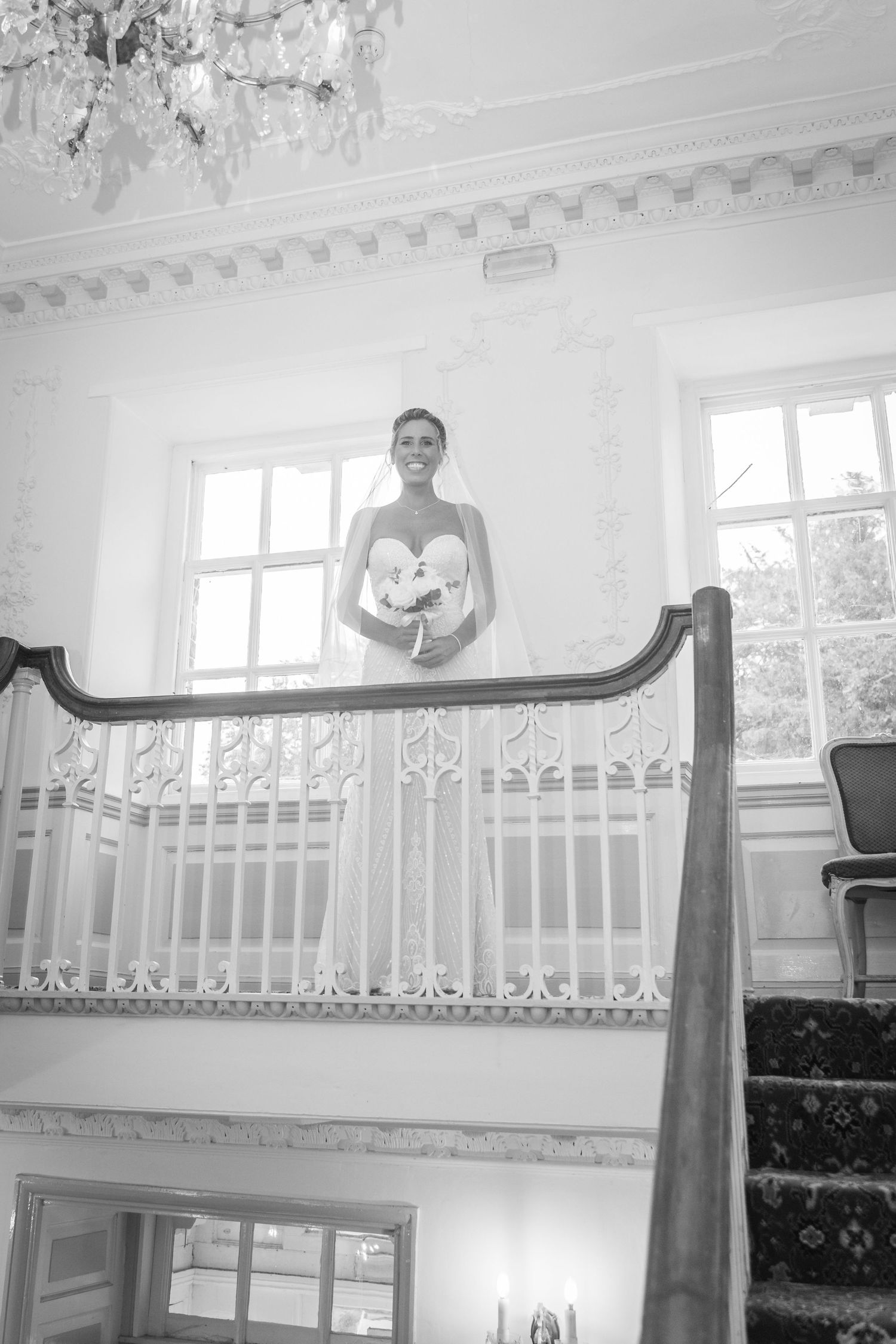 A long curved wooden banister rail with ornate white spindles along a staircase in an elegant interior space.