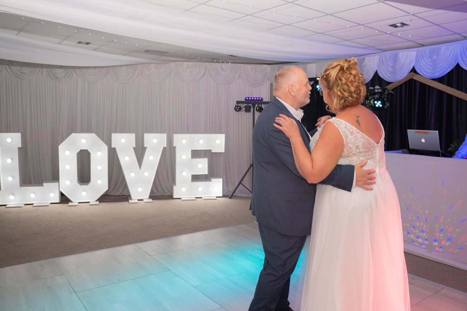 Wedding reception dance floor with illuminated LOVE letters and couples dancing.