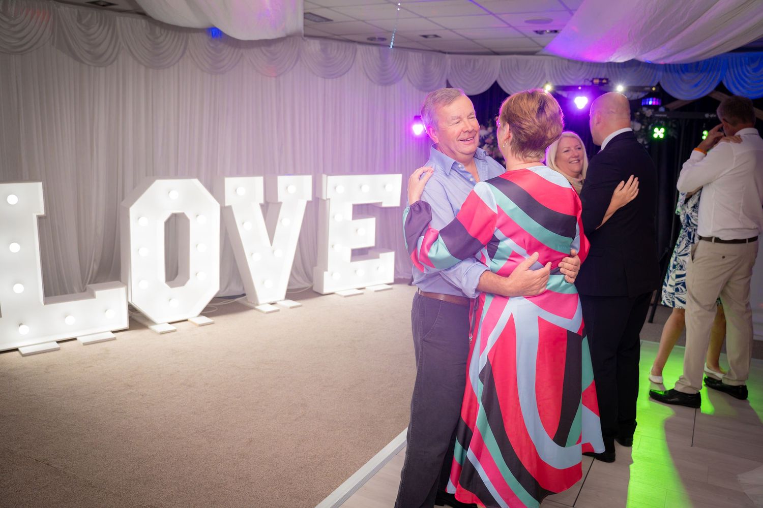 Dance party scene with colorful lighting and large illuminated LOVE letters display.