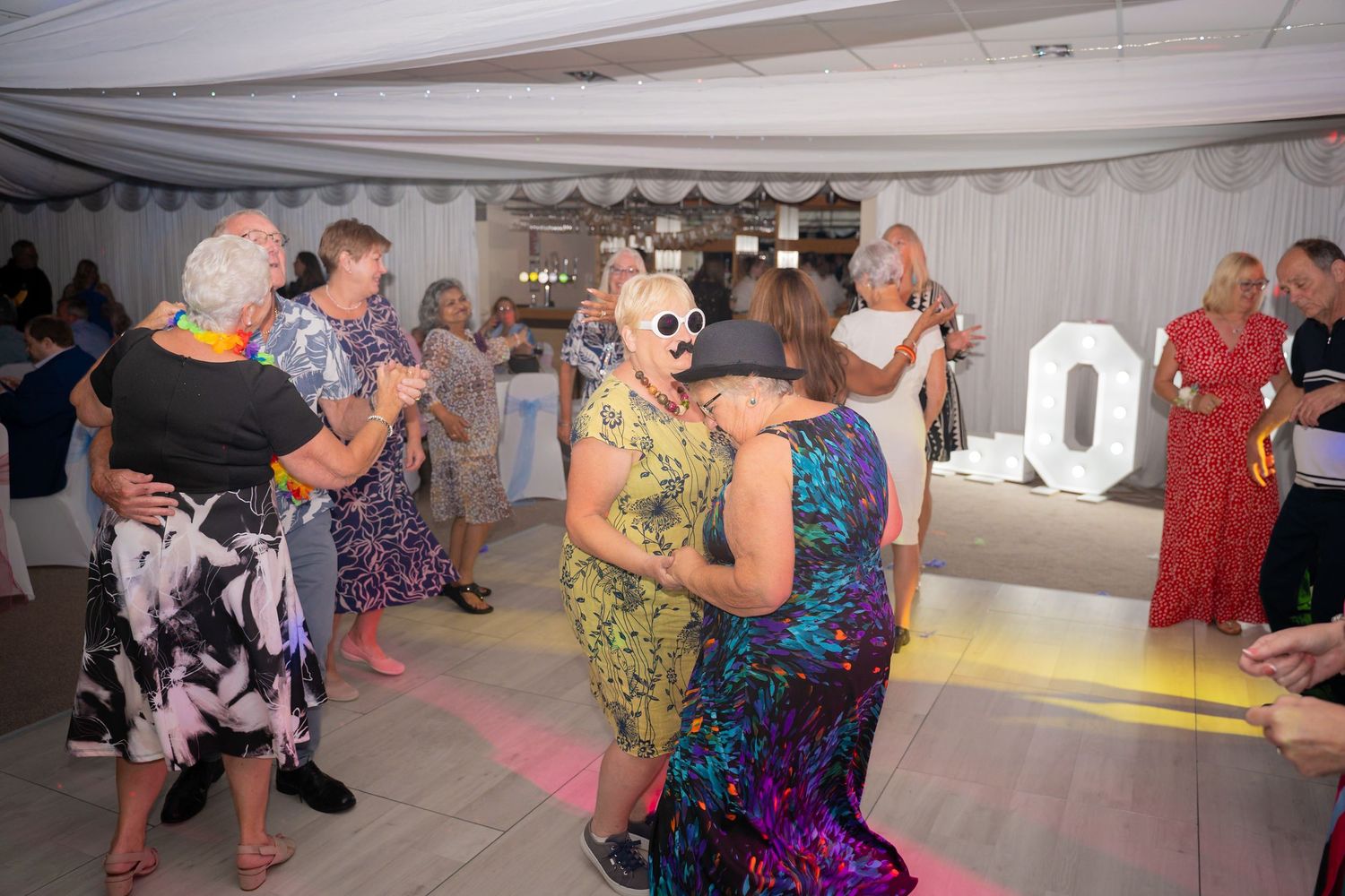Wedding reception dance floor with guests enjoying the celebration in colorful attire.
