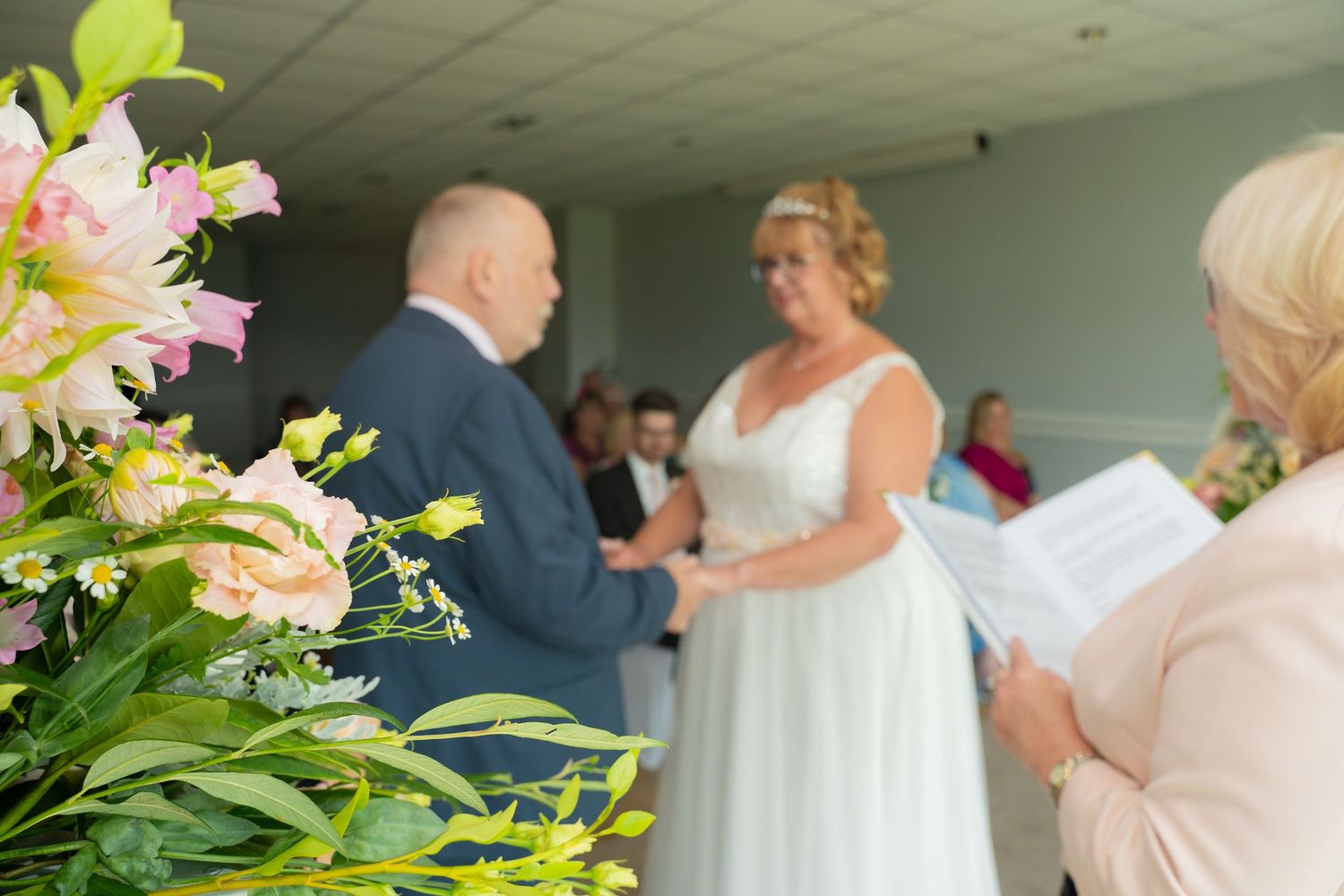 Beautiful floral arrangement with pink lilies decorates an indoor ceremony space.