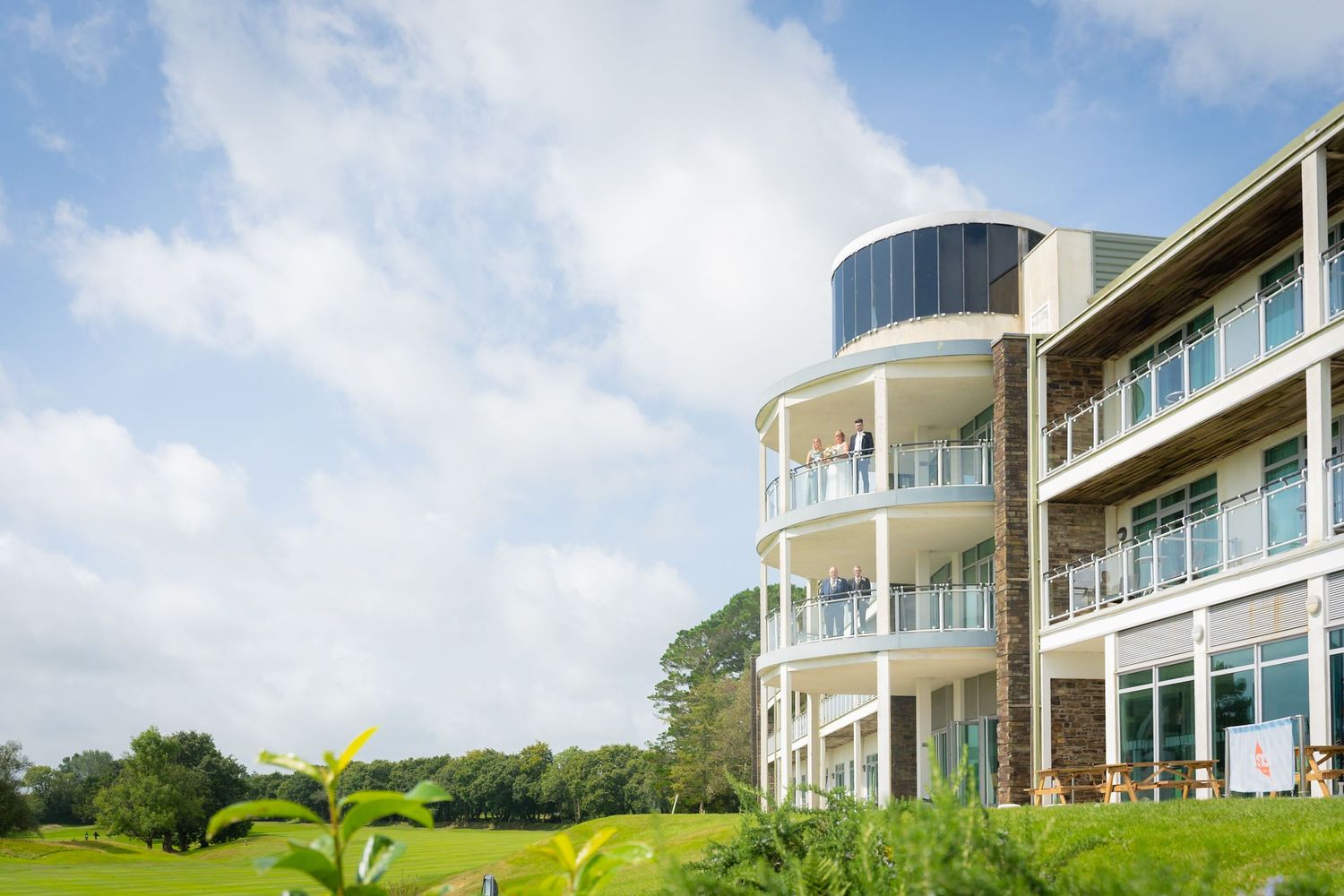 Modern luxury beachfront homes with curved balconies and glass walls overlooking a lush green landscape.