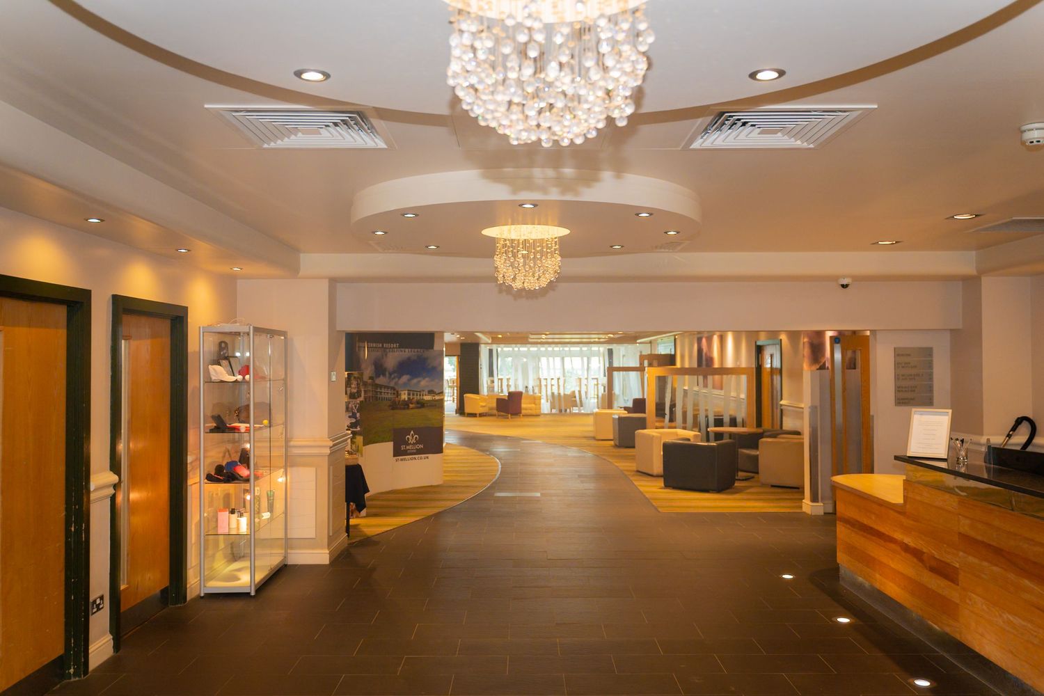 Modern event space with crystal chandeliers and elegant white decor illuminated by warm lighting.