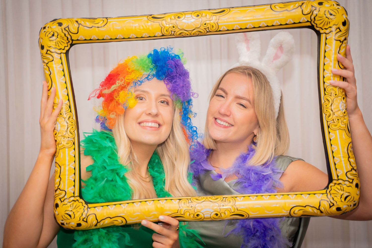 Party guests posing with ornate gold picture frames at a festive photo booth.