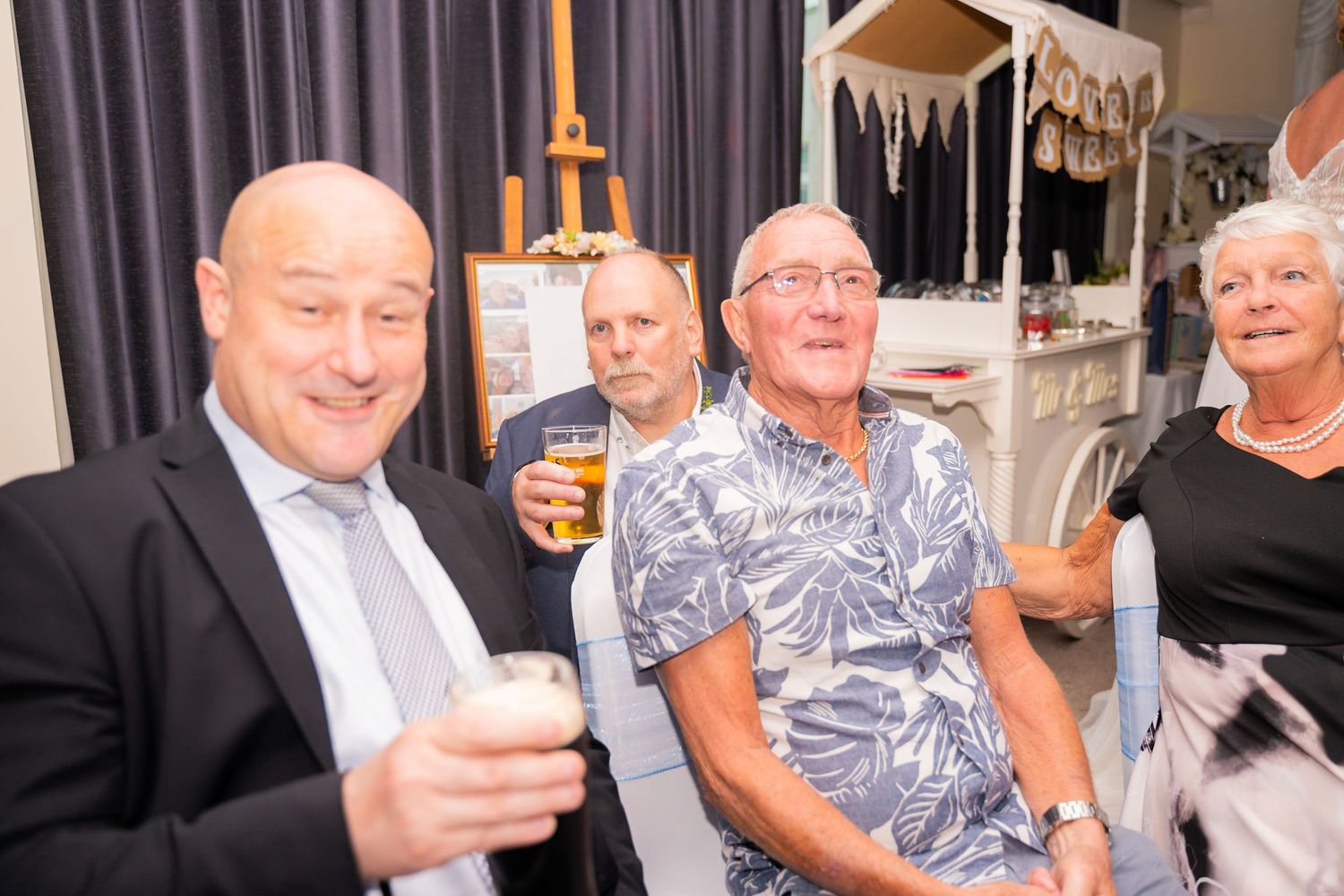 Group of party guests enjoying drinks and conversation at an indoor social gathering.