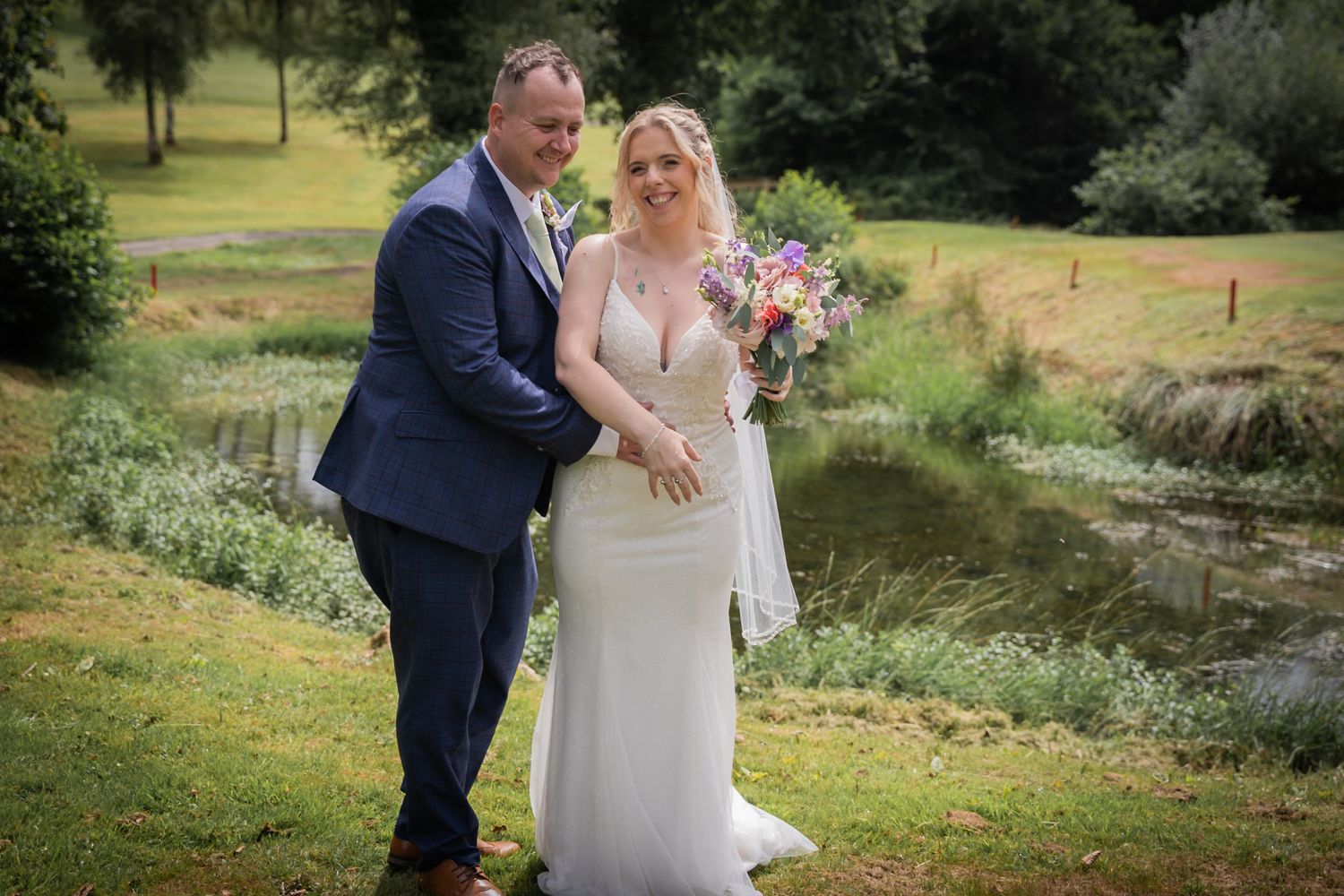 A romantic wedding couple shares intimate moments in a lush garden setting during their outdoor summer celebration.