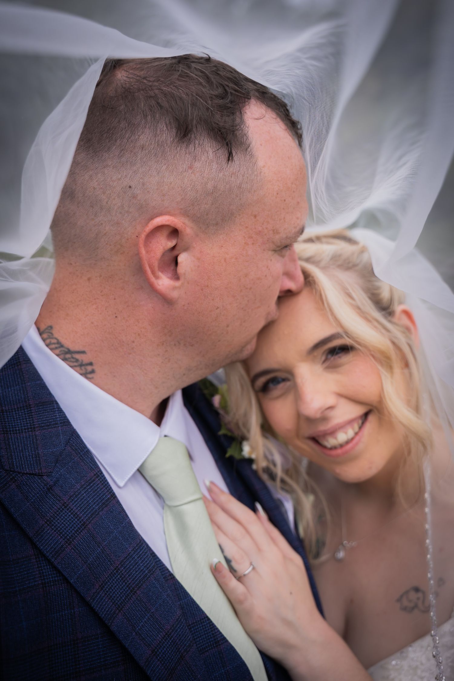 Romantic wedding couple sharing intimate moments against a soft blurred background.