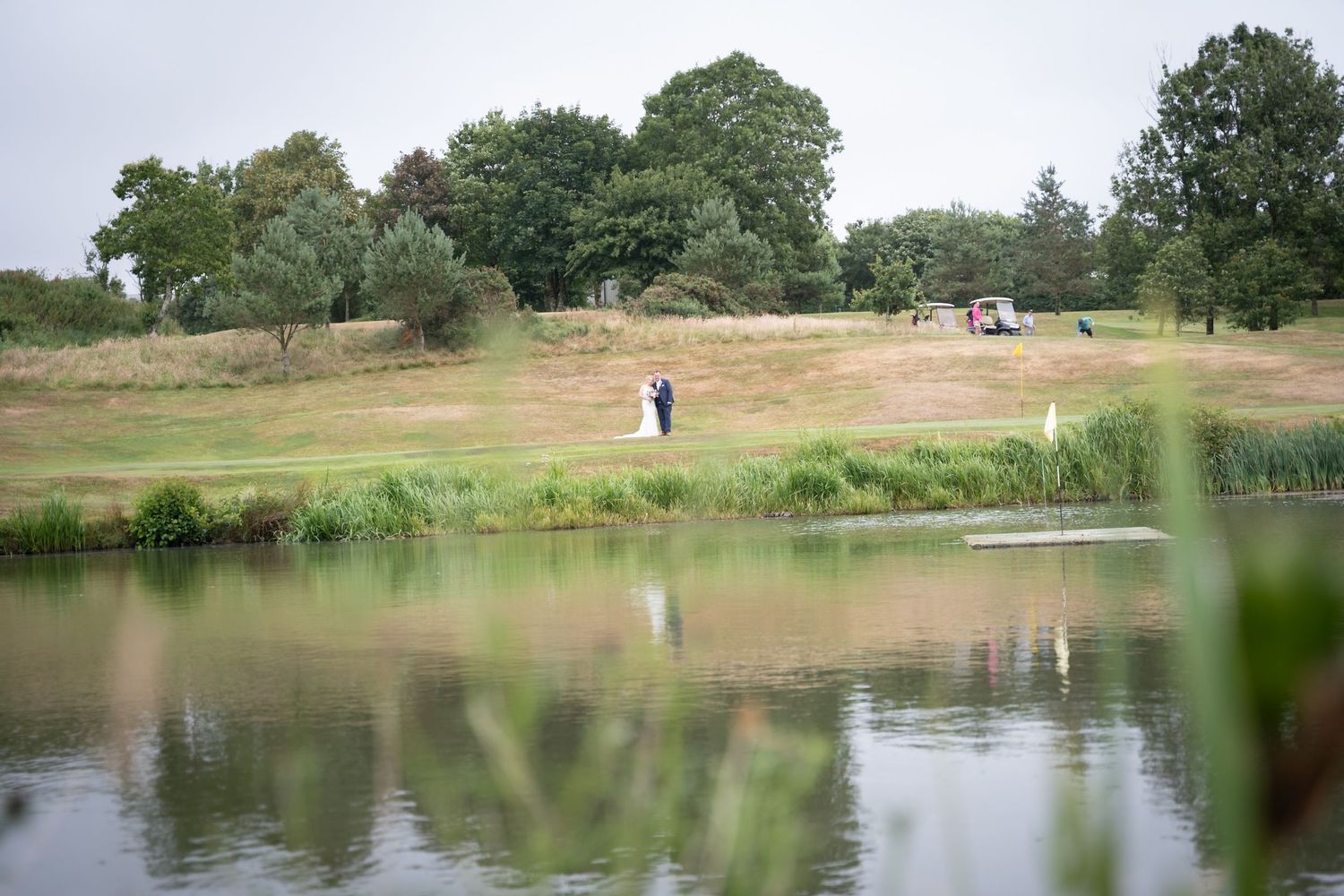 A scenic golf course landscape with rolling hills, trees, and a tranquil pond reflecting the natural surroundings.
