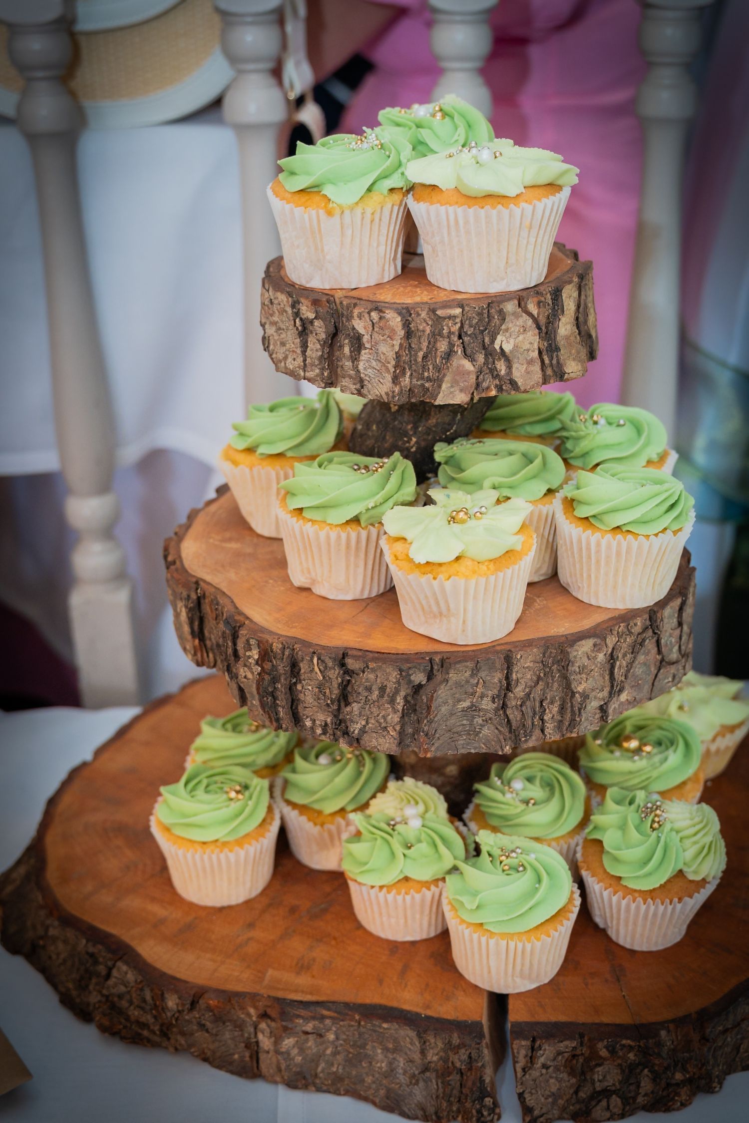 Rustic wedding cupcake display featuring green frosted cupcakes arranged on tiered wooden log slices.