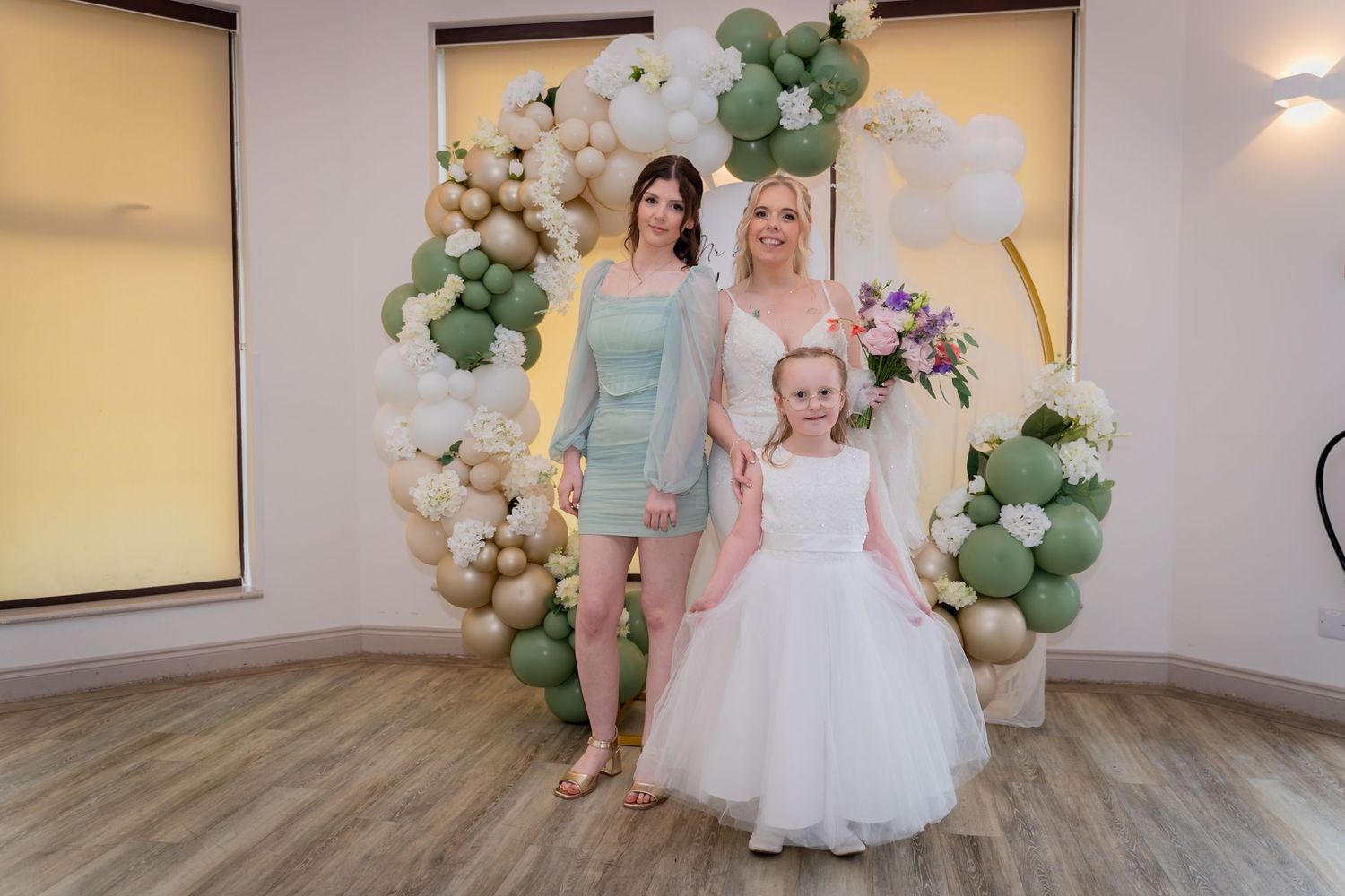 A wedding reception venue decorated with elegant balloon arches in green and gold colors creates a romantic atmosphere.