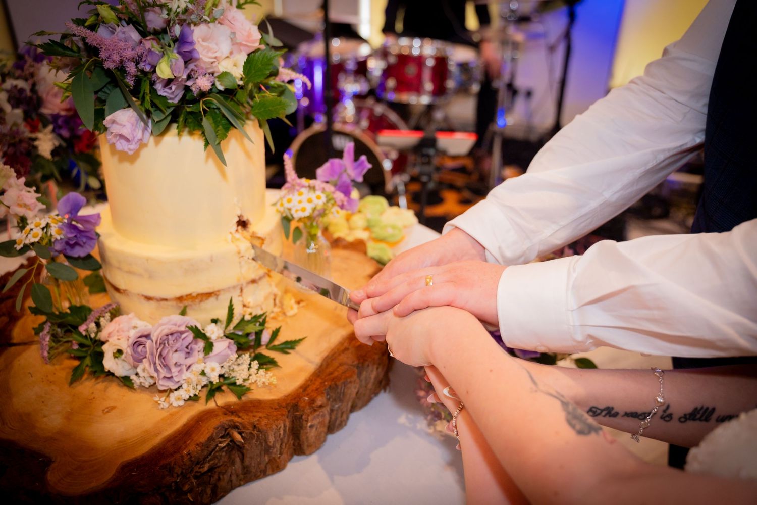 Wedding cake cutting ceremony with floral decorations and romantic lighting.