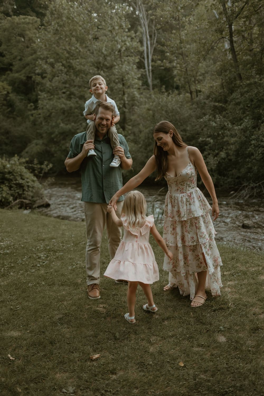 A family enjoys a casual stroll together in a wooded area during golden hour.