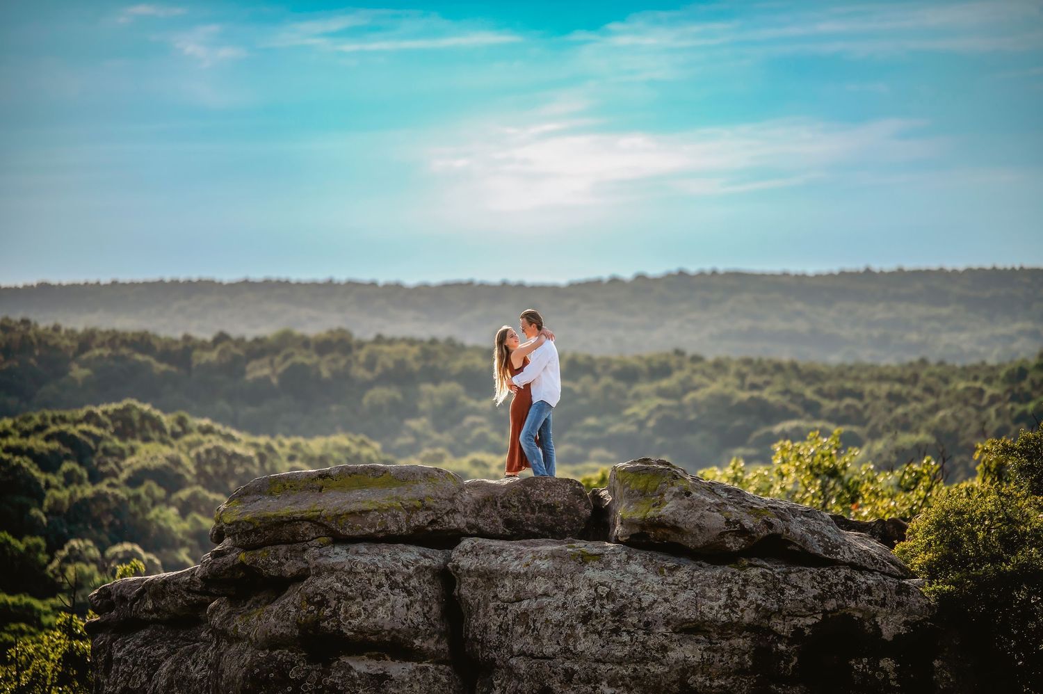 Romantic couple portraits taken on rocky cliffs with dramatic mountain landscapes in the background.