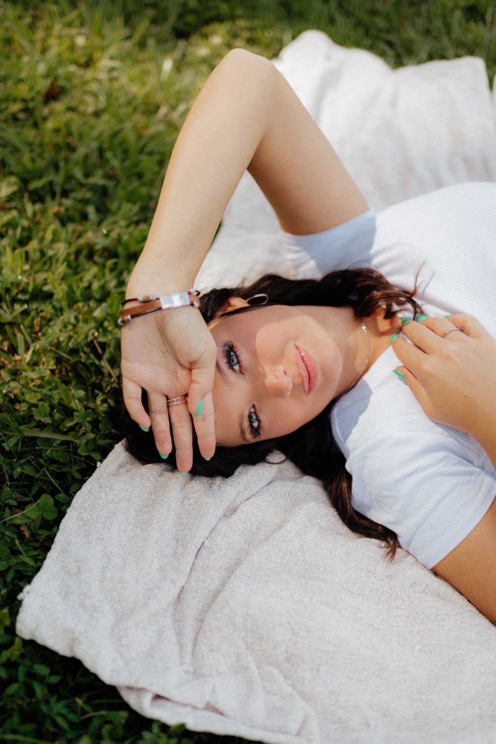 A young woman laying on a blanket in the grass during a lifestyle portrait session in Ellijay, GA by Ella Monroe Photography