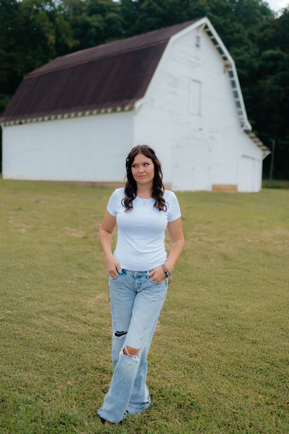 An outdoor individual portrait session in front of a rustic white barn in Ellijay, Georgia by Ella Monroe Photography.